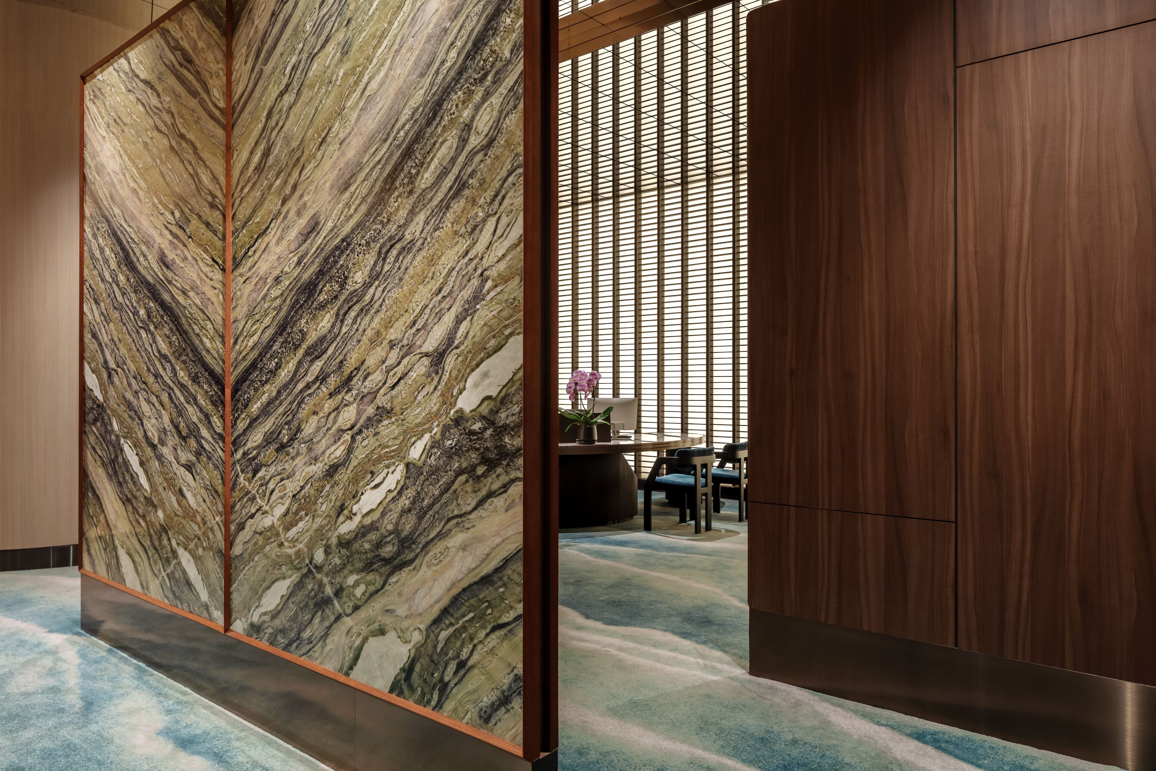 Une pièce dotée d’un grand mur à texture, d’un plancher en bois et d’un espace salon avec une table et des chaises.