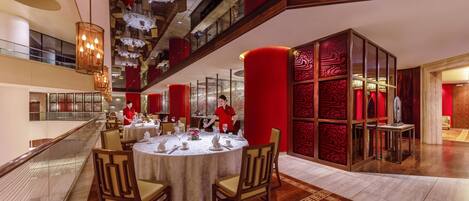 A modern hotel lobby with a spacious seating area, a glass railing, and a decorative red wall.
