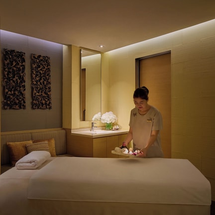 A hotel room with a bed, a bedside table with a lamp, and a mirror.