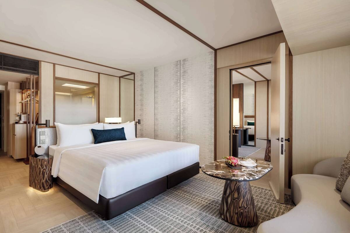 Una habitación de hotel moderna con una cama grande, una mesita de noche y un área de descanso con una pequeña mesa.