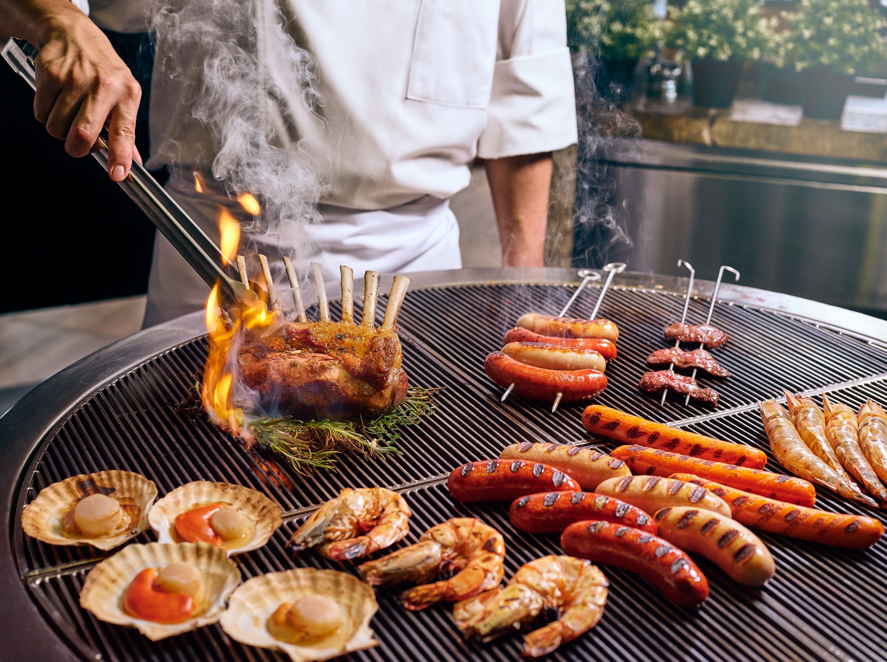 A grill with various meats and seafood, including sausages, shrimp, and scallops.