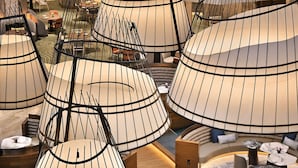 Un moderno vestíbulo de hotel con zonas de estar curvas y originales, y una escalera central de madera.