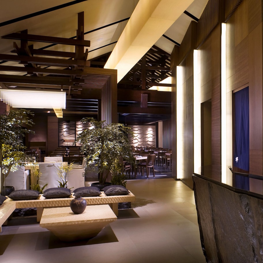 A modern interior with a seating area, a bar with shelves of bottles, and a wooden wall design.
