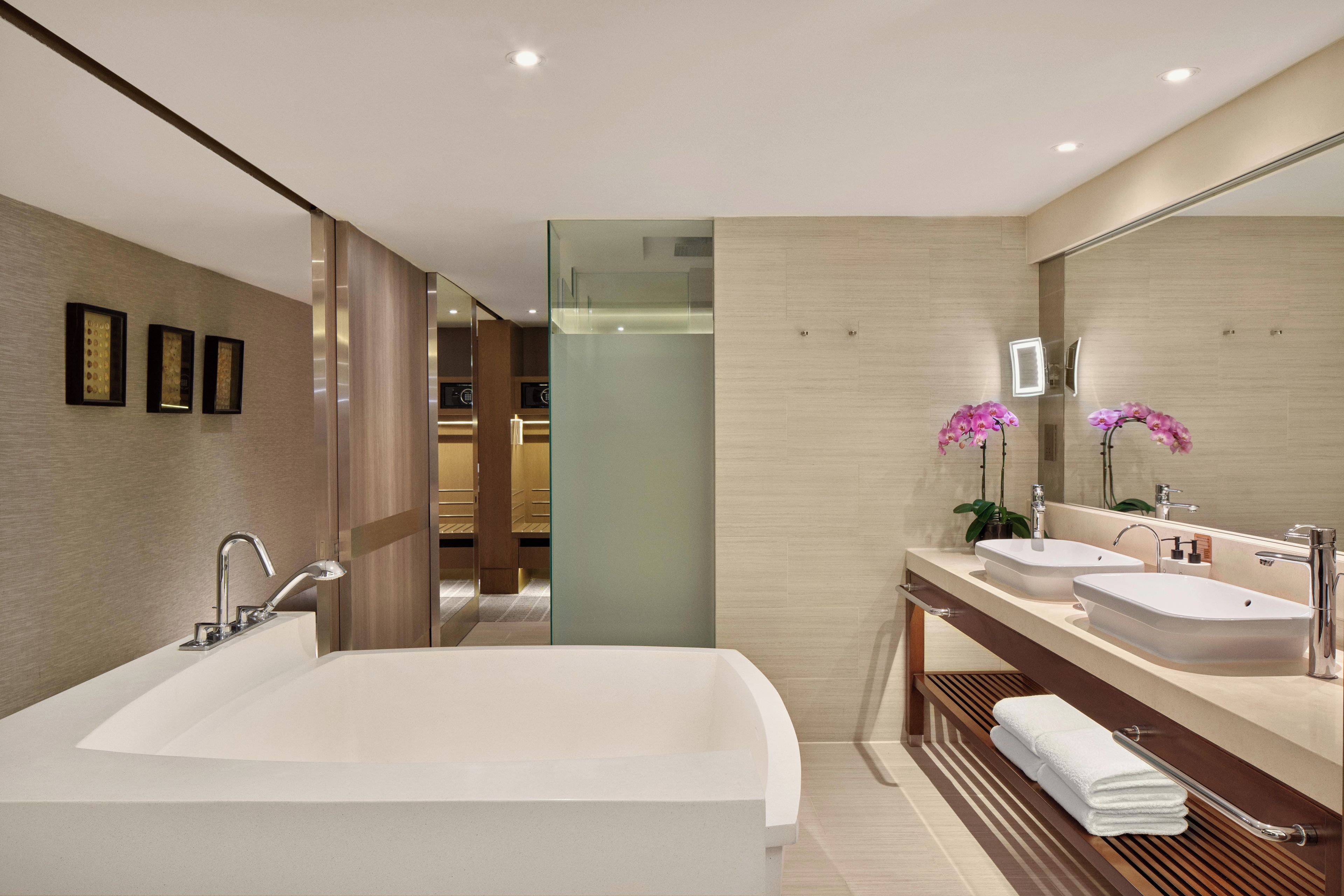A modern bathroom with a large bathtub, two sinks, and a mirror.