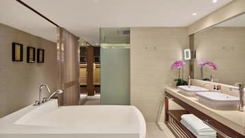 A modern bathroom with a large bathtub, two sinks, and a mirror.
