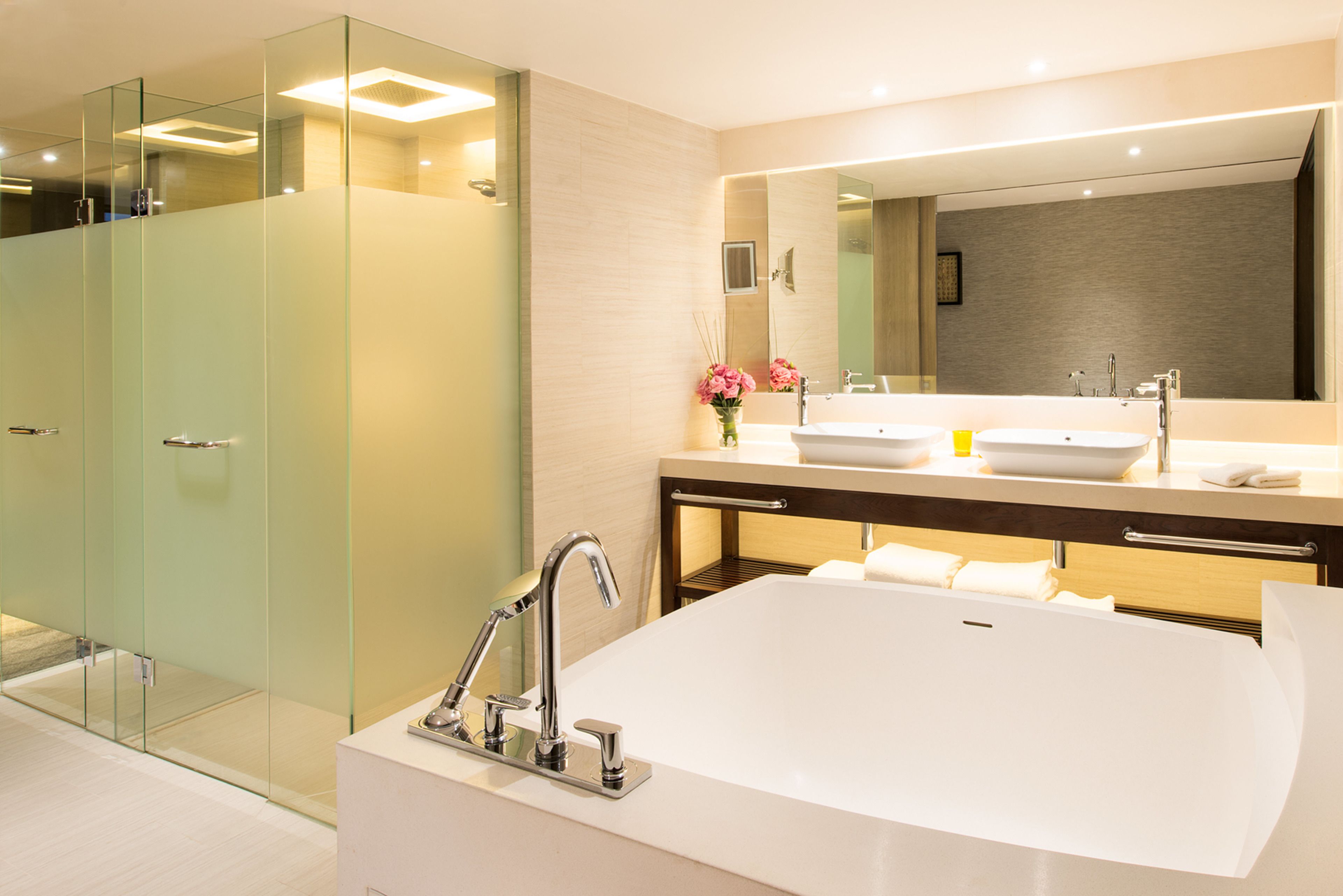 A modern bathroom with a glass-enclosed shower, a large freestanding bathtub, and dual sinks.