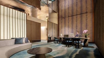 Un intérieur moderne avec un canapé aux lignes courbes, une table basse ronde et un bureau avec un ordinateur.