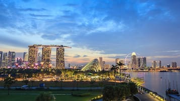 A cityscape with modern skyscrapers, a prominent curved building, and a waterfront park.
