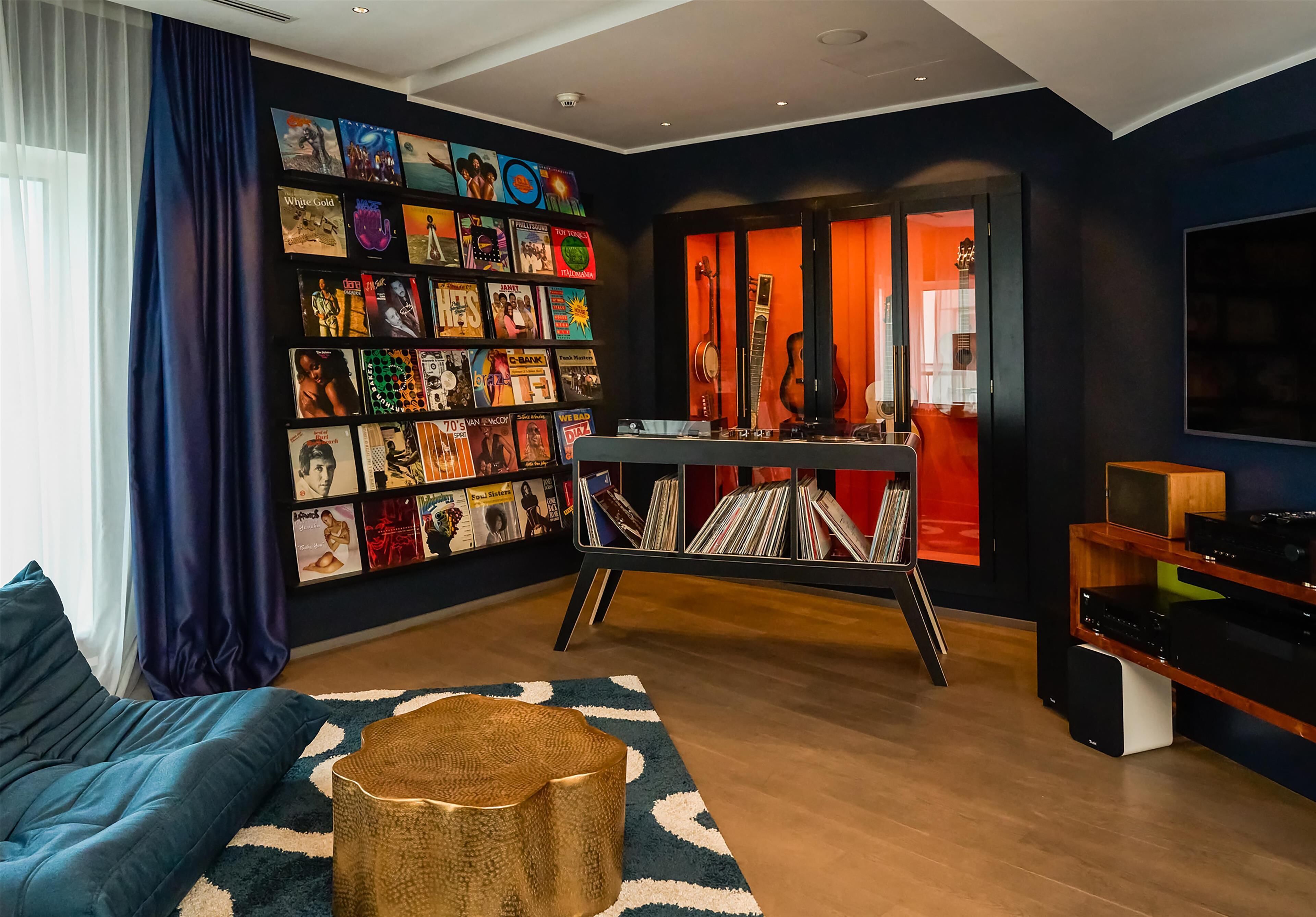 A living room with a blue sofa, a coffee table, a record shelf, and a guitar.