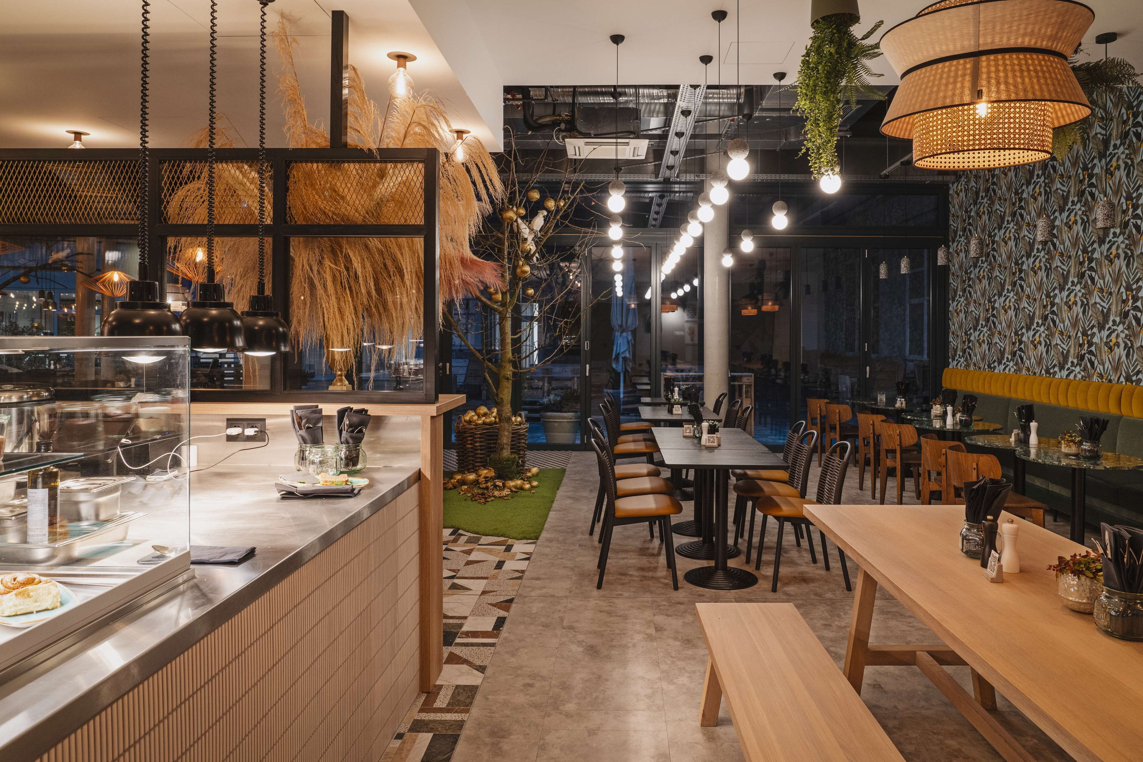 A modern restaurant interior with a counter, seating area, and decorative plants.