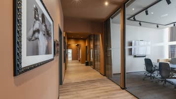 Un interior de oficina moderno con suelo de madera, paredes de vidrio y una fotografía enmarcada en la pared.