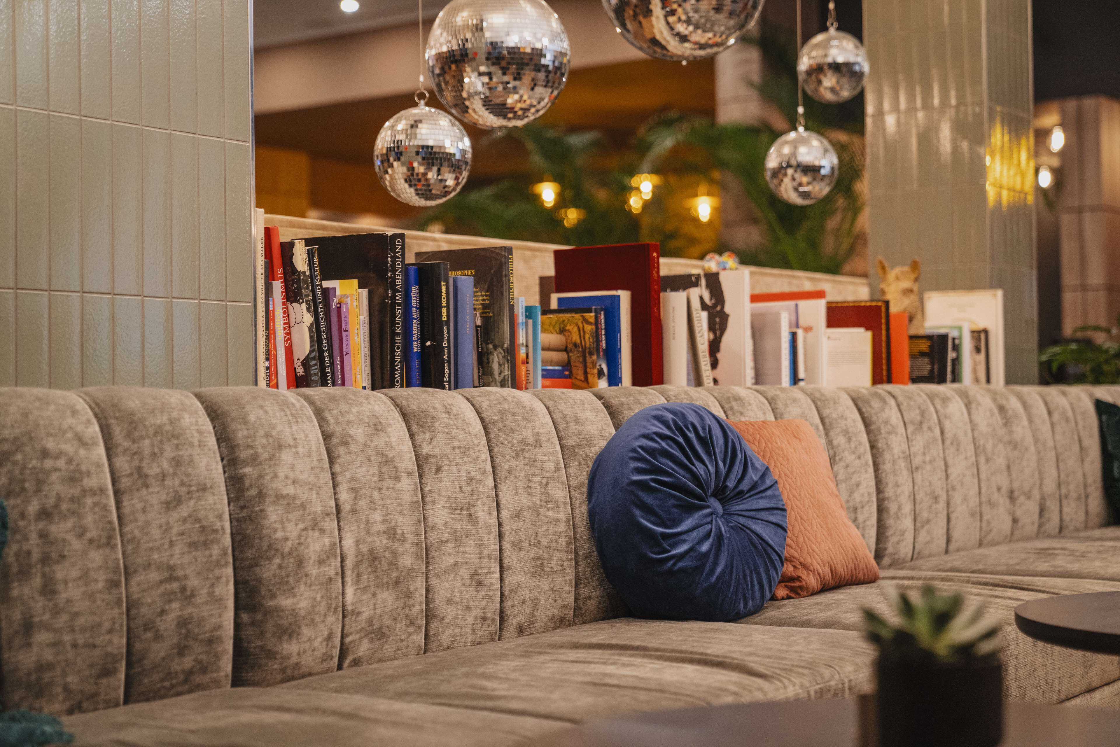 A modern living room with a sofa, bookshelves, and decorative disco balls.