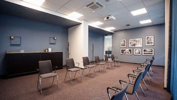 A conference room with a reception desk, chairs arranged in rows, and framed pictures on the walls.