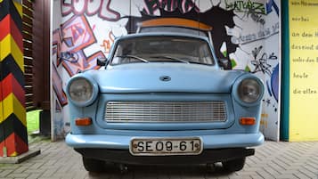 Un coche azul antiguo estacionado frente a un muro con grafitis coloridos.