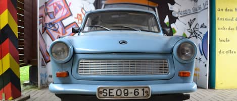 A vintage blue car parked in front of a wall with colorful graffiti.