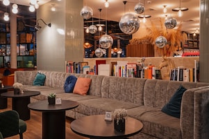 Un área de estar moderna con un sofá, mesas redondas y espejos decorativos.