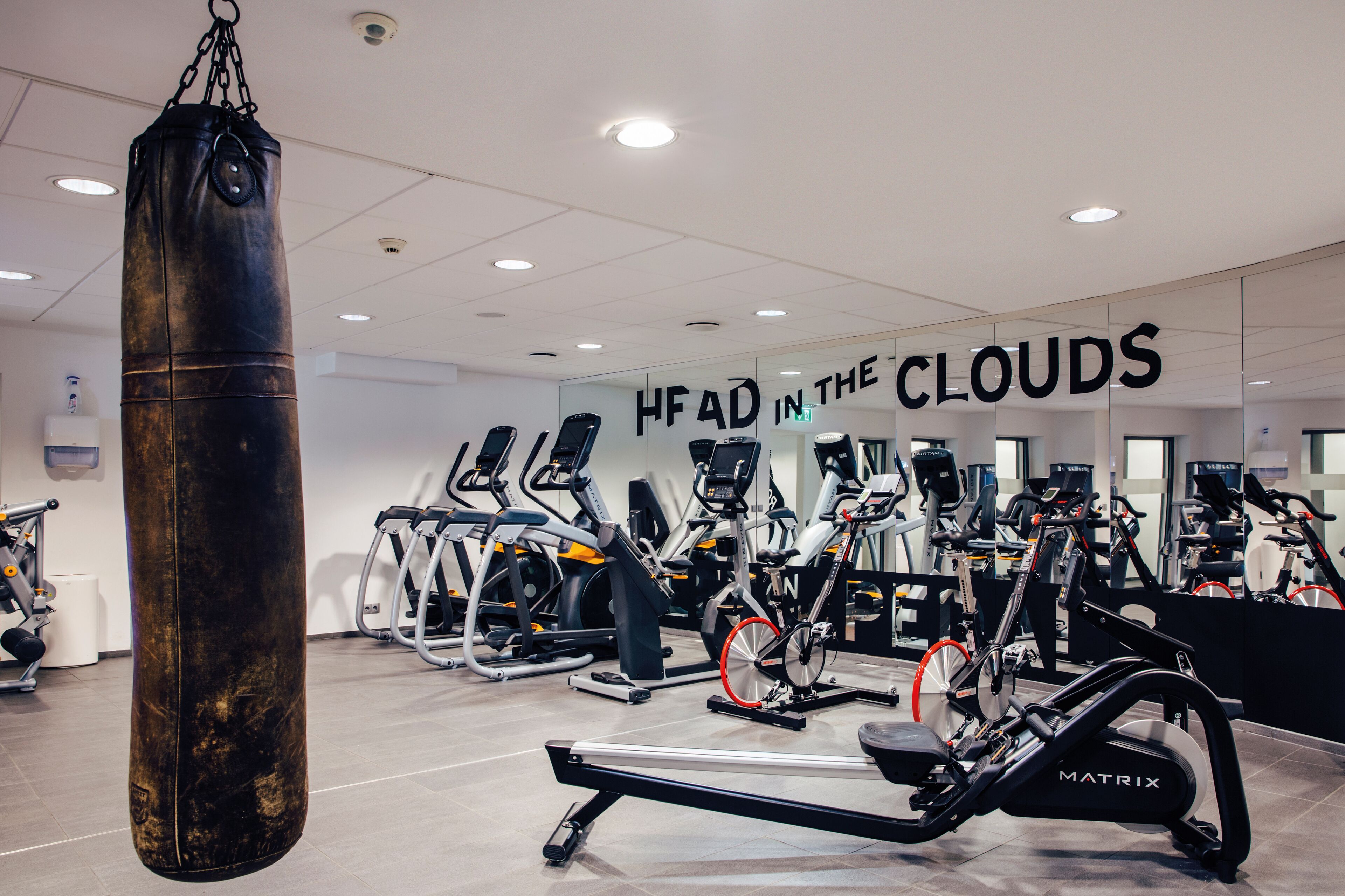 Une salle de sport équipée de divers appareils d’exercice, notamment des tapis de course et des vélos d’appartement, ainsi qu’un sac de frappe.
