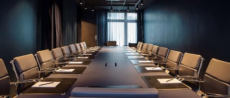 Una sala de conferencias con una mesa larga, varias sillas y un proyector.