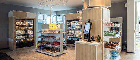 A modern retail store with refrigerated sections, a self-checkout, and a variety of products on shelves.