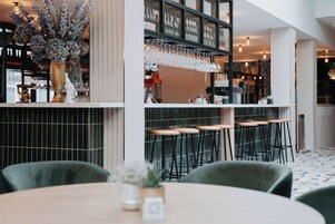 Una zona de bar con mostrador alto, varios taburetes y un jarrón decorativo.