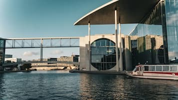 Un edificio moderno con fachada de vidrio, un puente y una barca en el agua.