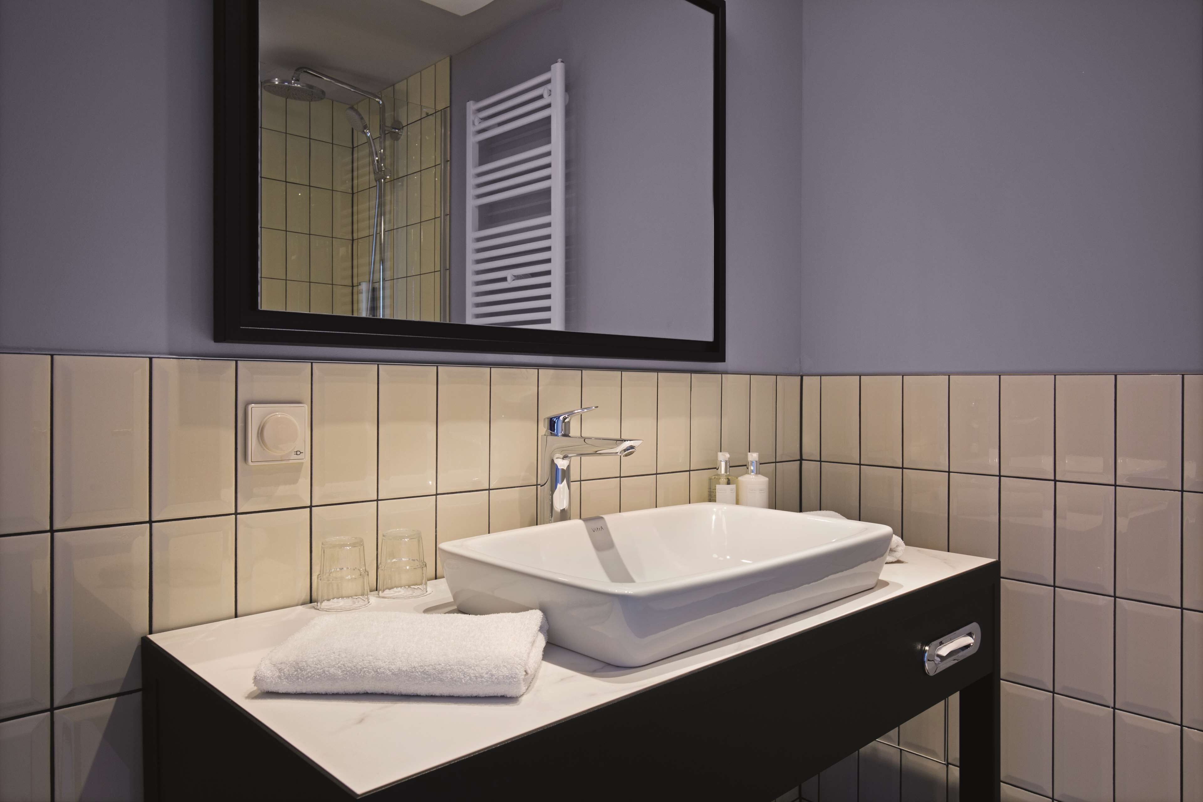 A bathroom with a white sink, a mirror, and a towel on the counter.