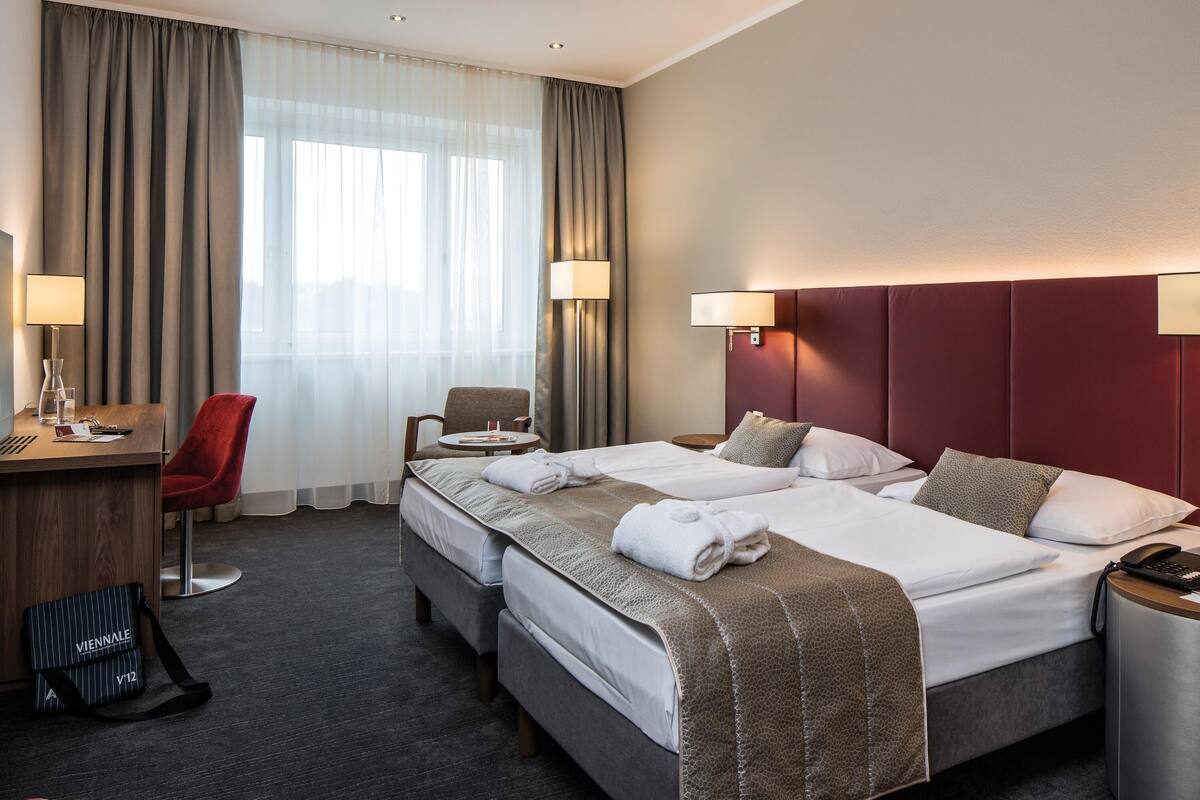 Une chambre d’hôtel avec un lit double, un bureau avec une chaise, une petite table et une chaise rouge.