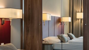 A hotel room with a bed, bedside lamps, a round table, and a mirror reflecting the room. - Austria Trend Europa Salzburg (Salzburg)