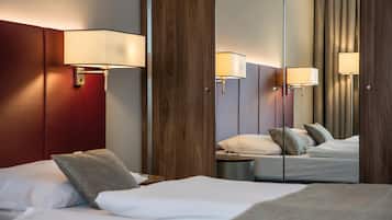 A hotel room with two beds, wooden paneling, and wall-mounted lamps.