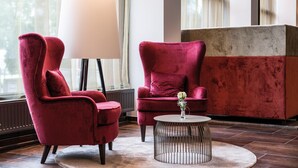 A modern room with two red velvet armchairs, a round coffee table, and a large floor lamp. - Austria Trend Europa Salzburg (Salzburg)