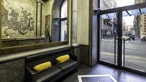 Un hall d’entrée avec un canapé noir, un grand miroir et une vue sur la rue.