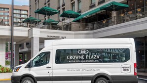 Un fourgon blanc est garé devant un bâtiment orné de parasols verts et d’une enseigne indiquant « hauteur libre : 3,35 mètres ».