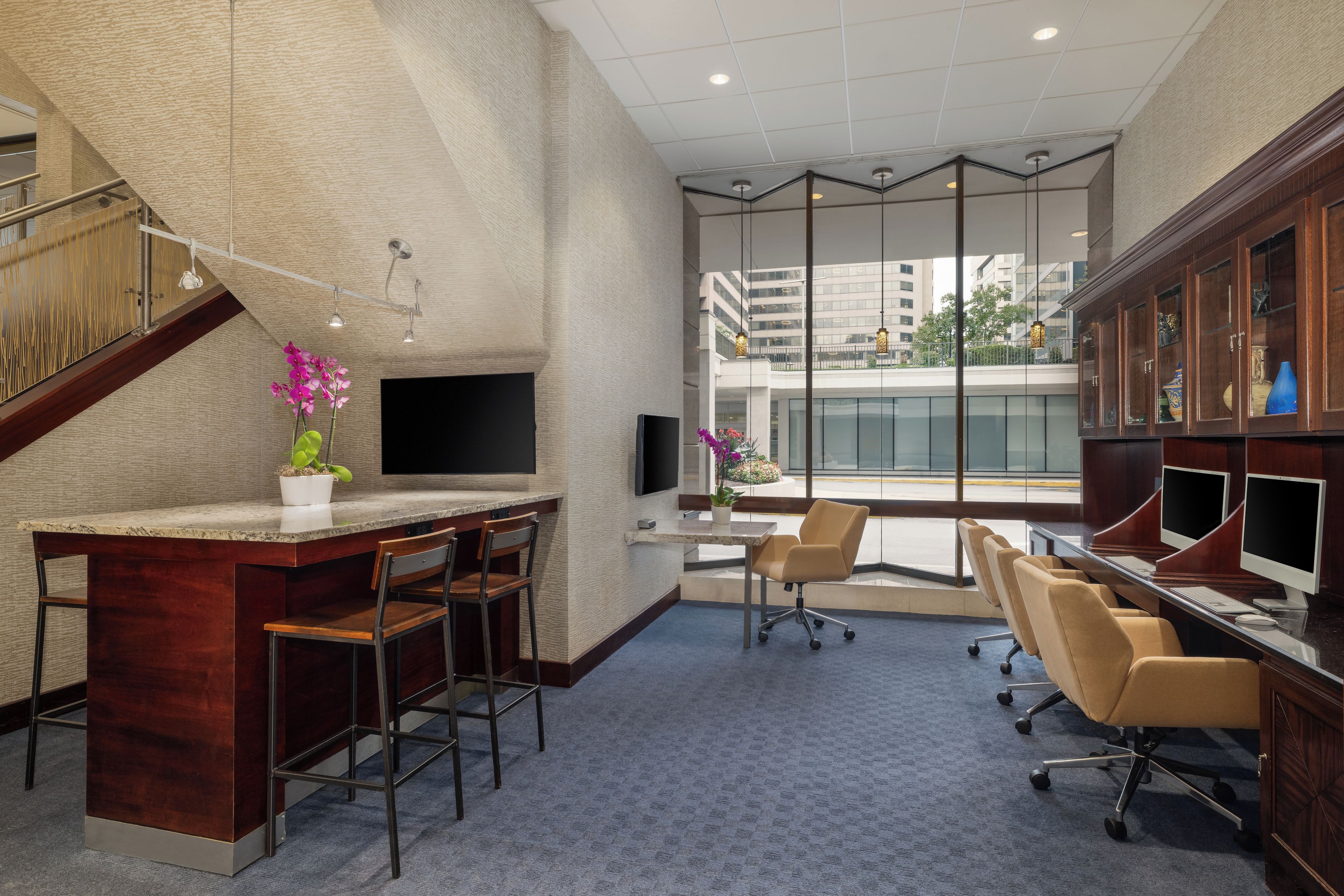Un espace de bureau moderne comprenant un bureau, des chaises, un escalier et une vue sur l’extérieur.