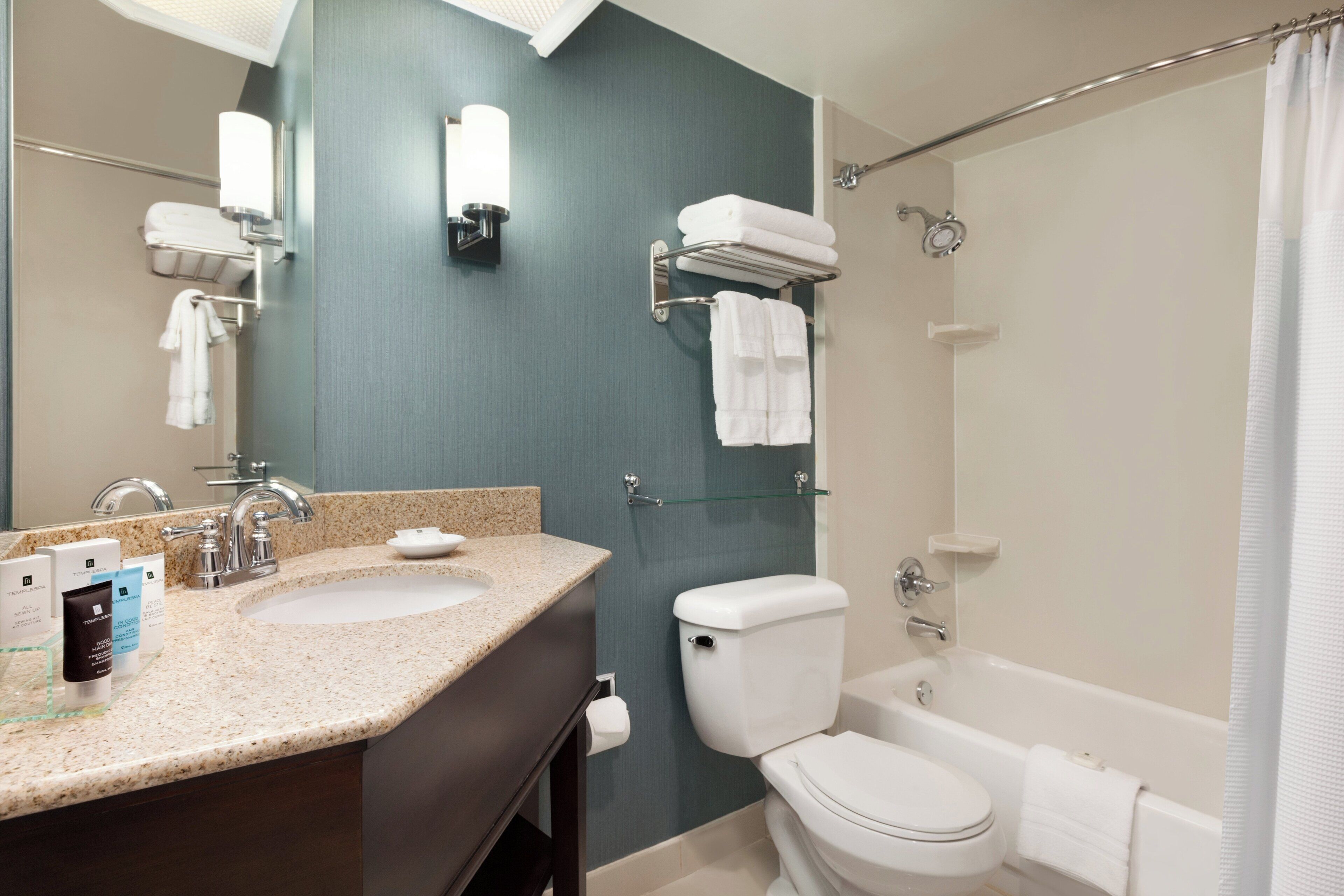 A bathroom with a sink, mirror, towel rack, toilet, and bathtub.
