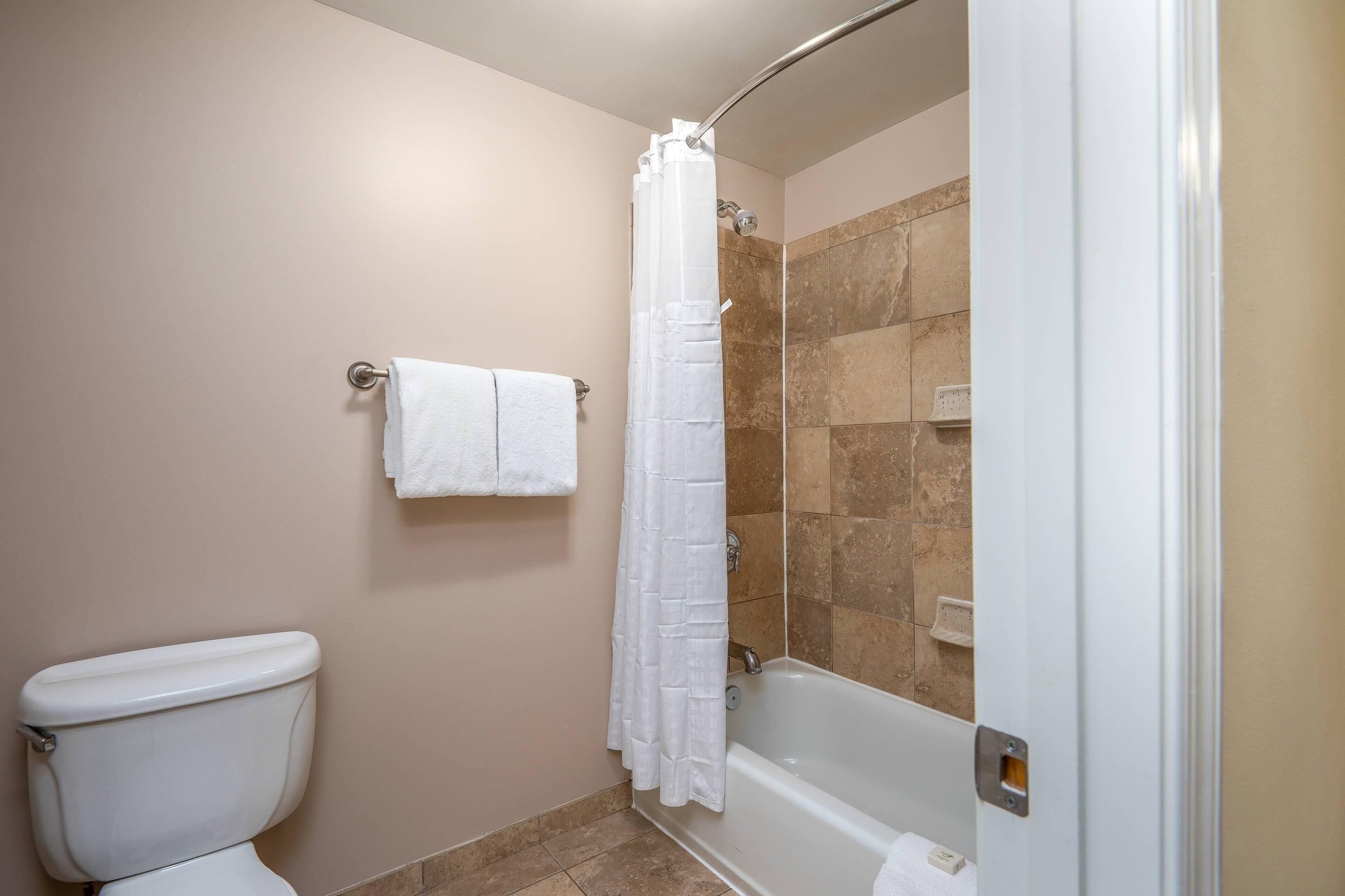 A bathroom with a toilet, a shower with a glass door, and a bathtub.