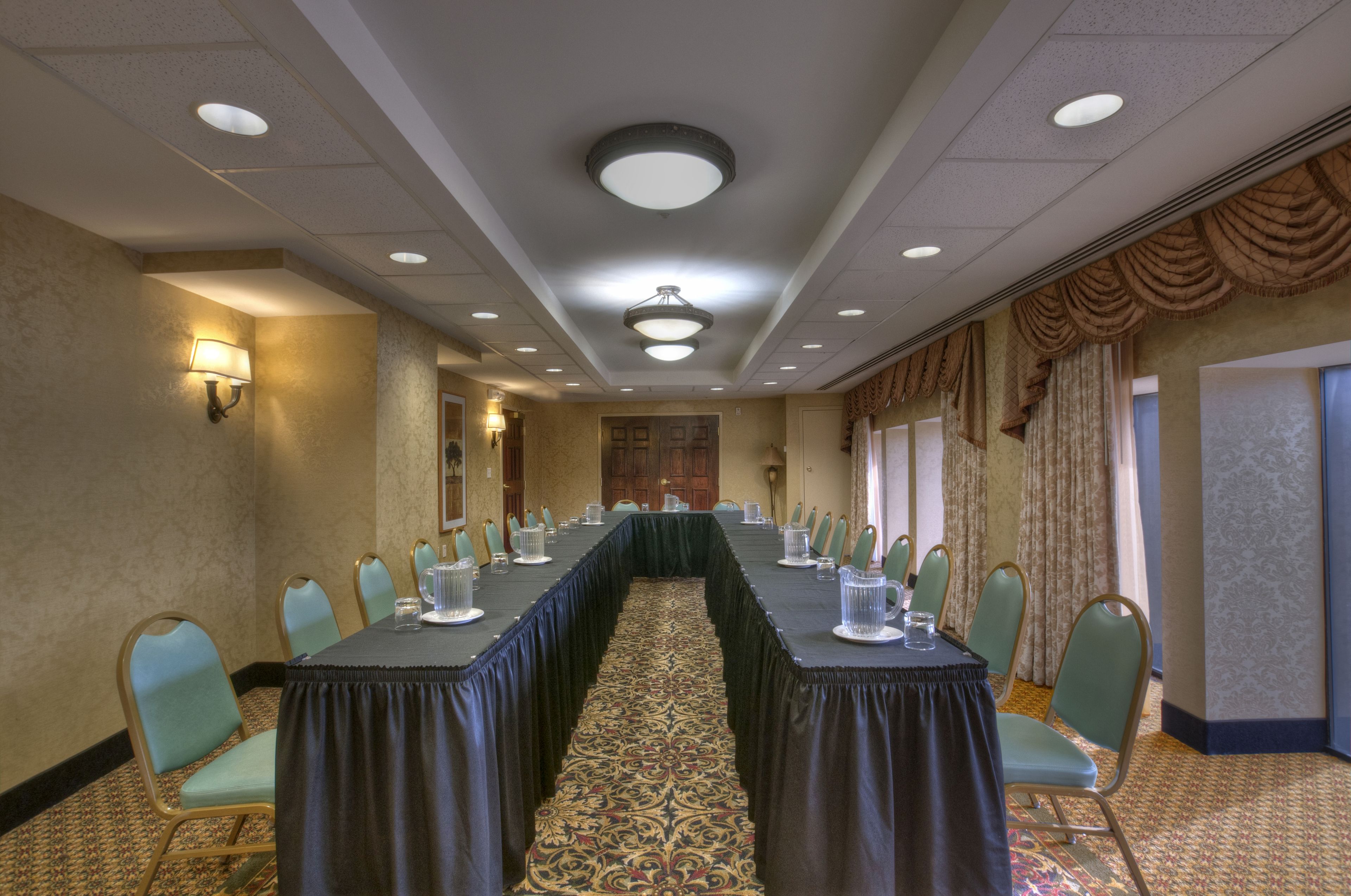 A conference room with a long table, chairs, and a patterned carpet.