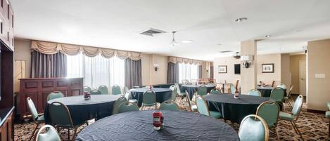 A conference room with multiple tables and chairs, a podium, and a carpeted floor.