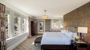 A hotel room with a large bed, a nightstand, a lamp, a mirror, and a view of the outside.