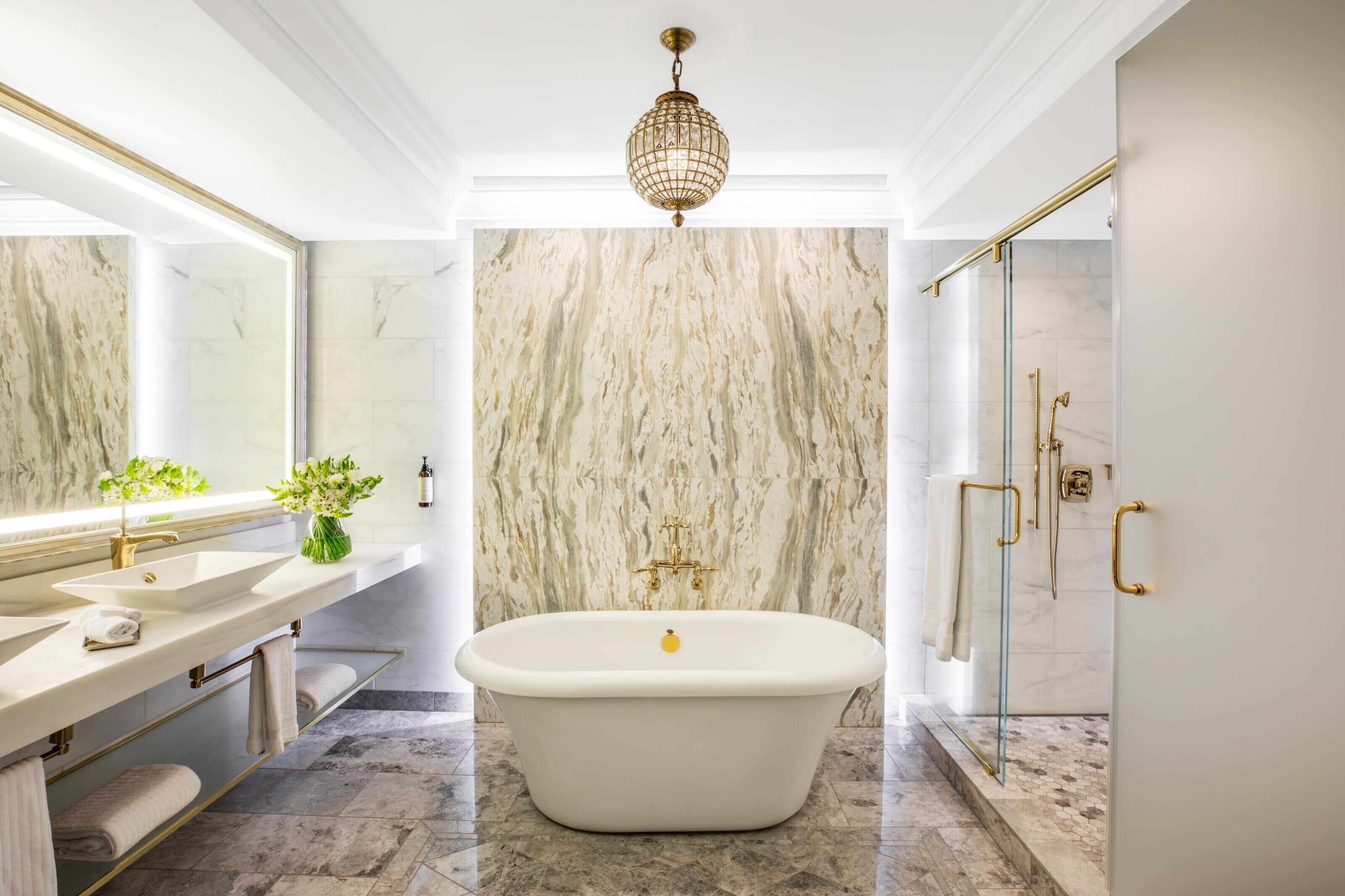 A bathroom with a freestanding bathtub, a large mirror, and a shower with glass doors.