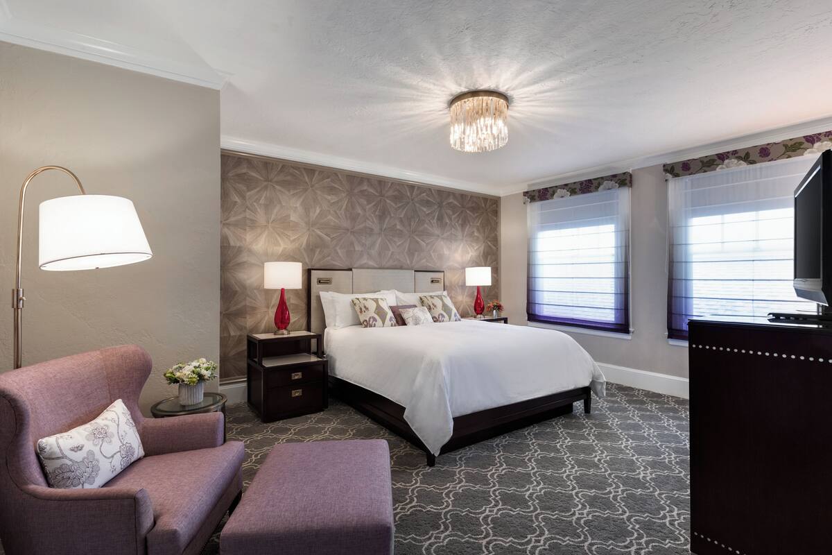 Ett modernt hotellrum med en stor säng, en soffa, ett skrivbord och en TV.