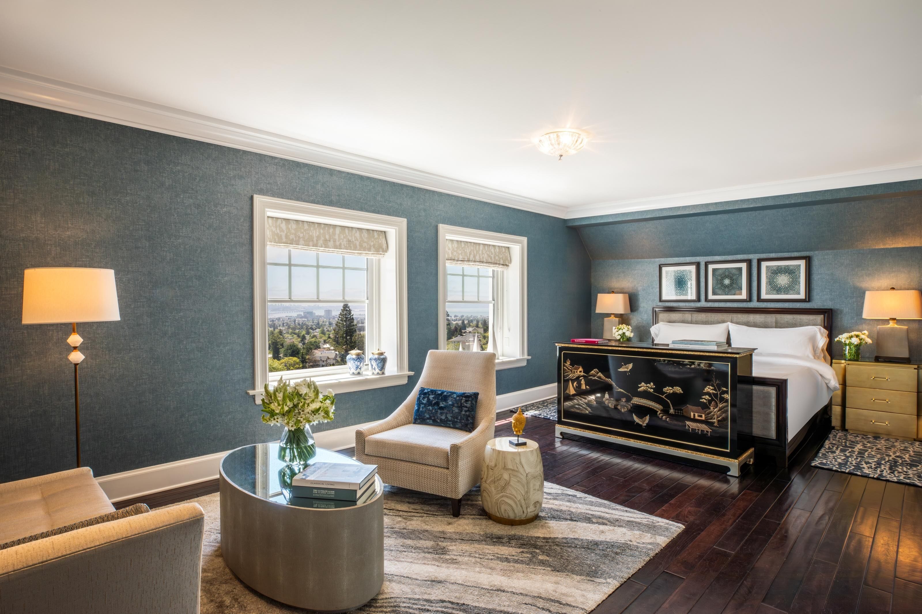 A bedroom with a bed, a chair, a round table, and a nightstand.