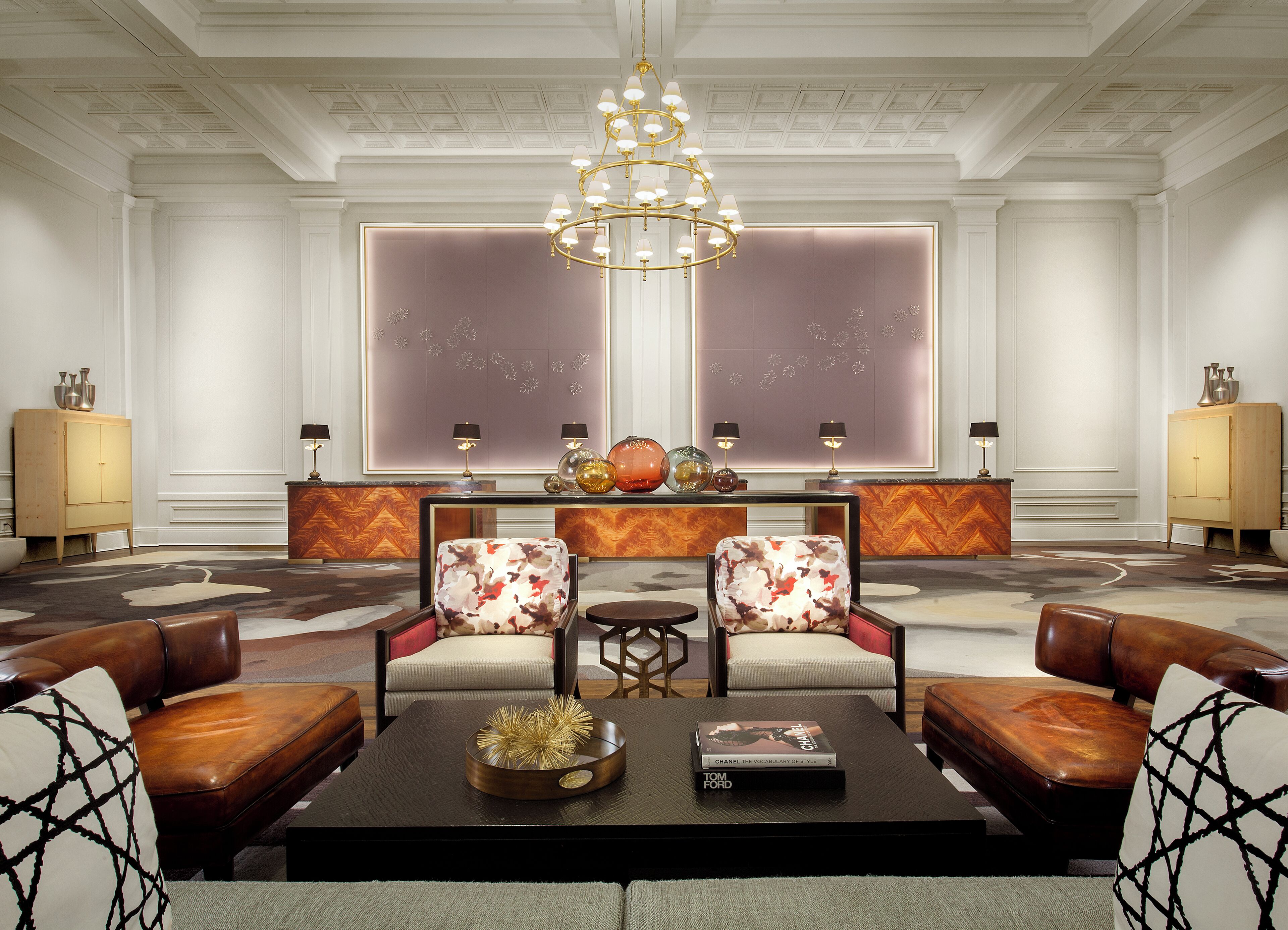 A spacious lobby with a central seating area, a decorative chandelier, and a large window with a view.