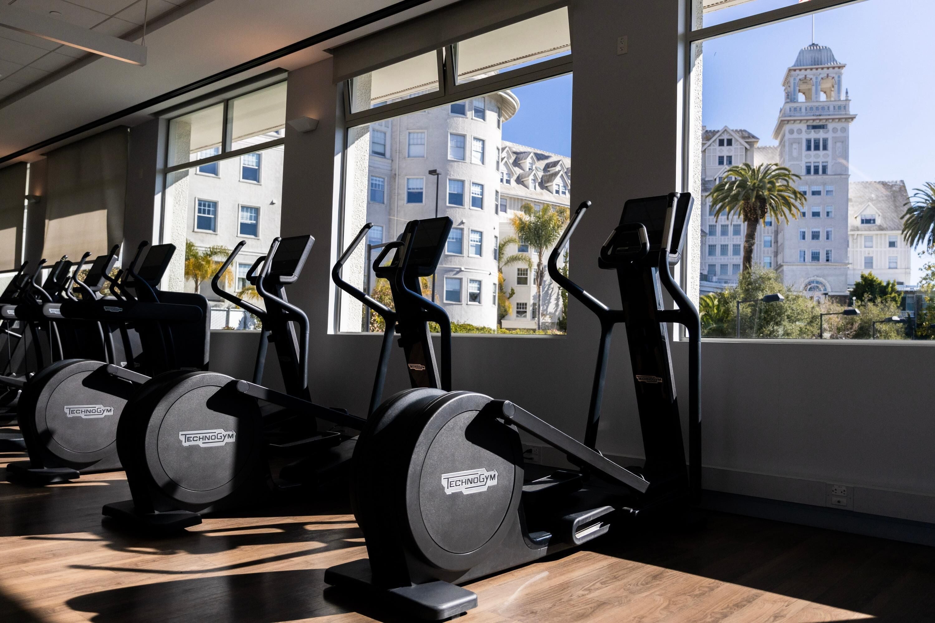 A gym with stationary bikes, a treadmill, and dumbbells.