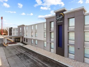 A Sleep Inn by Choice Hotels building with a modern facade, large windows, and a covered entrance.
