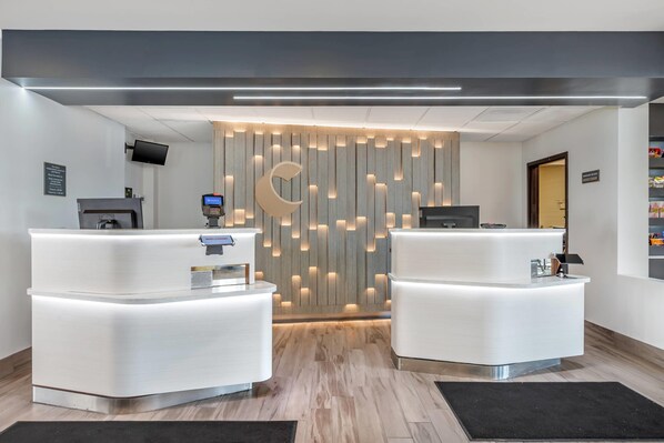 A reception area with two white reception desks, a wooden wall with vertical slats, and a crescent moon decoration. - Comfort Inn & Suites Arlington Heights - Buffalo Grove (Arlington Heights)