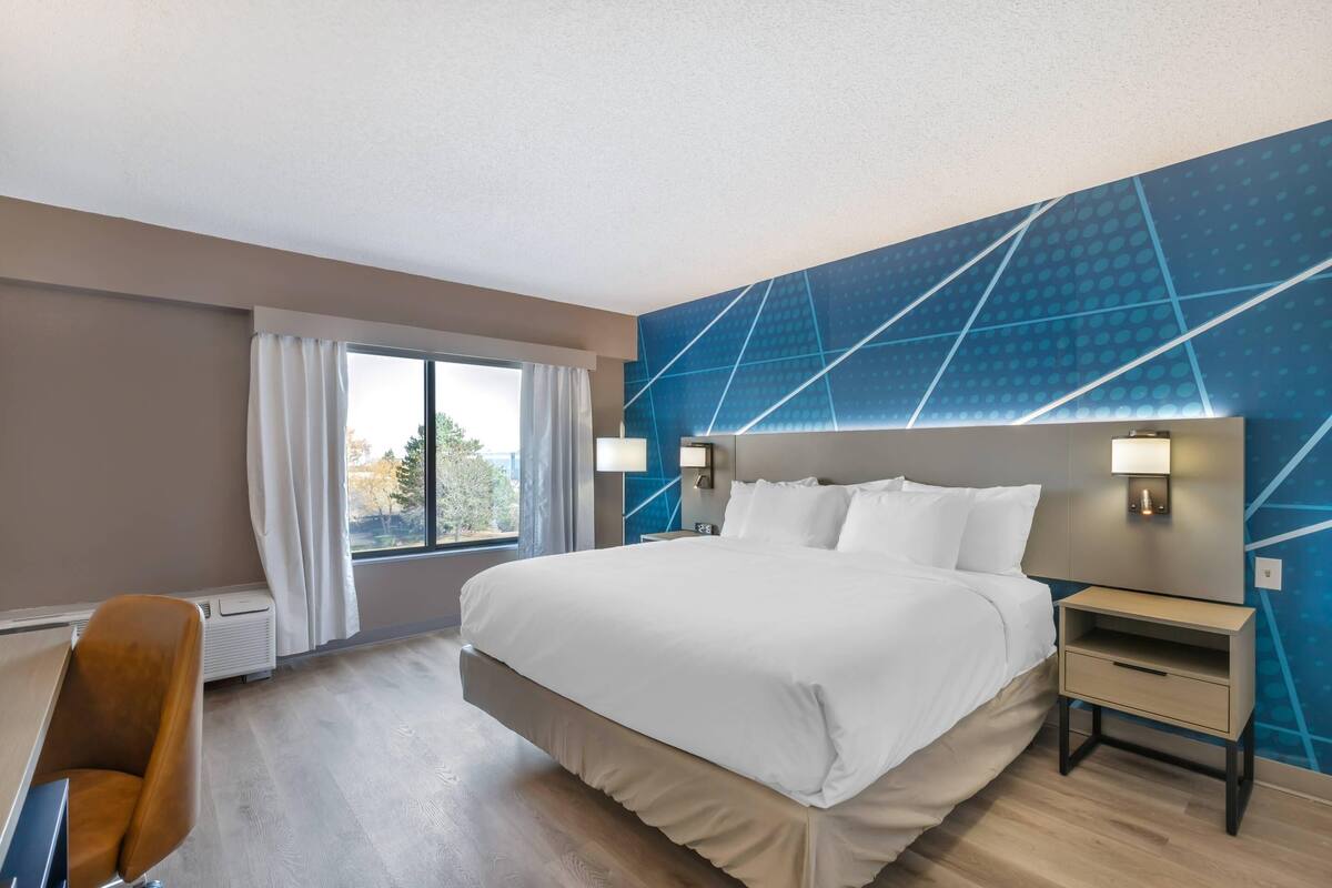 Una habitación de hotel con una cama grande, un escritorio y una ventana con cortinas.