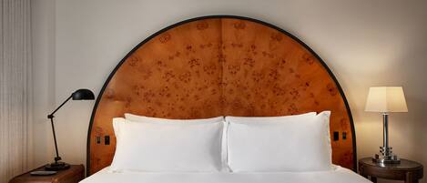 A hotel room with a large bed, a wooden headboard, two bedside tables, and a nightstand.