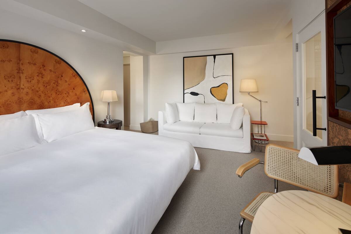 Una habitación de hotel con una cama grande, un sofá, una silla y un escritorio.