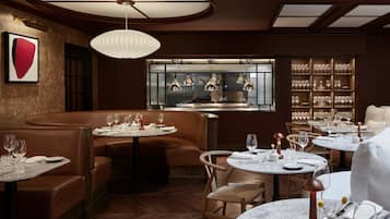 A restaurant with round tables, leather booths, and a wine rack.