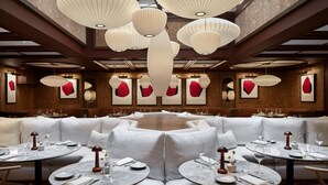 Un restaurant avec des tables rondes, des sièges rembourrés de couleur blanche et des lanternes en papier suspendues.